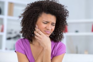 woman holding her jaw in pain